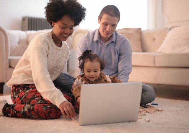 parents and baby looking at laptop